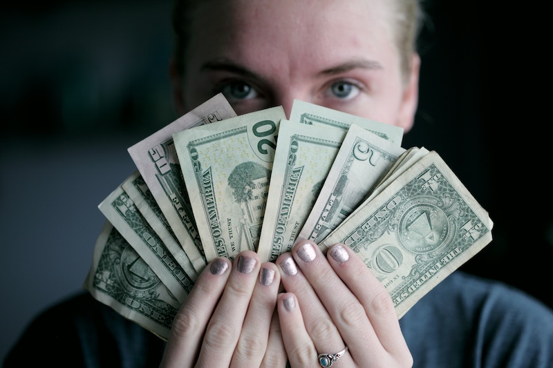 Young woman holding money in front of her face