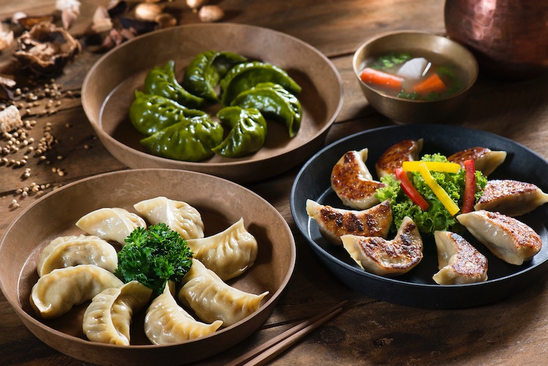 Three dishes of Chinese dumplings and soup on table