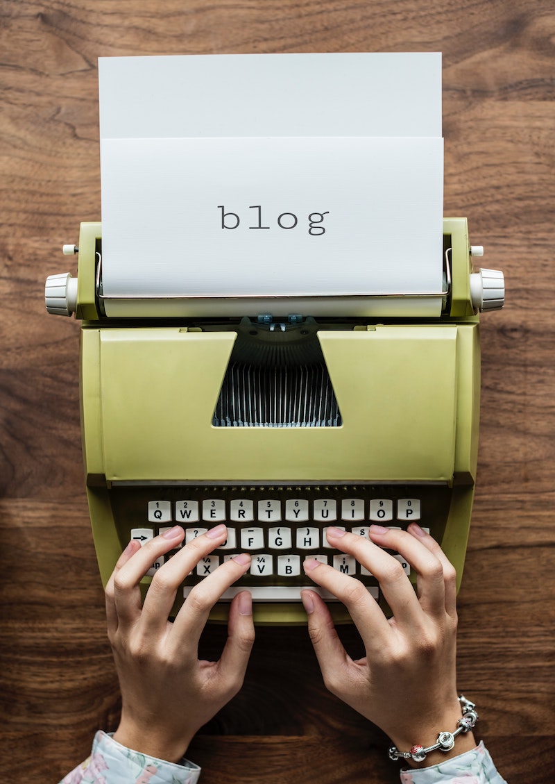 A green typewriter with a white sheet of paper that says blog